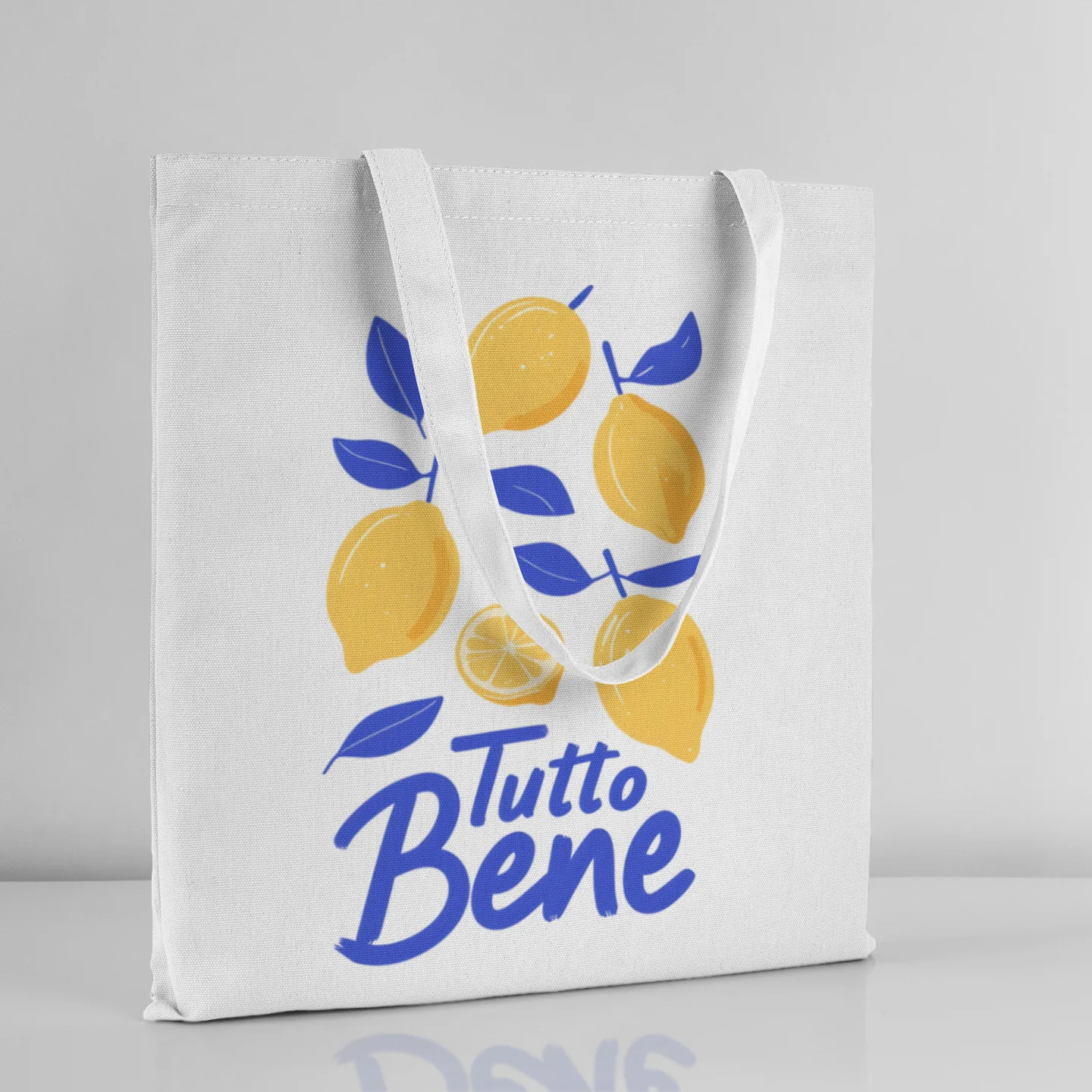 White tote bag with lemons and 'Tutto Bene' text on a gray background
