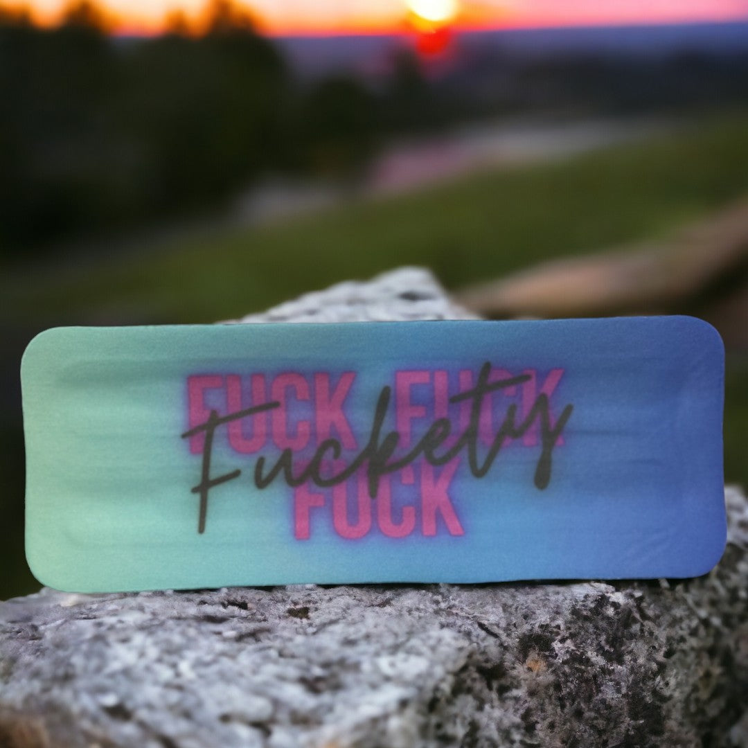 Custom drinkware koozie with vibrant, bold text showcased on a rock during sunset, perfect as unique gifts for any occasion.