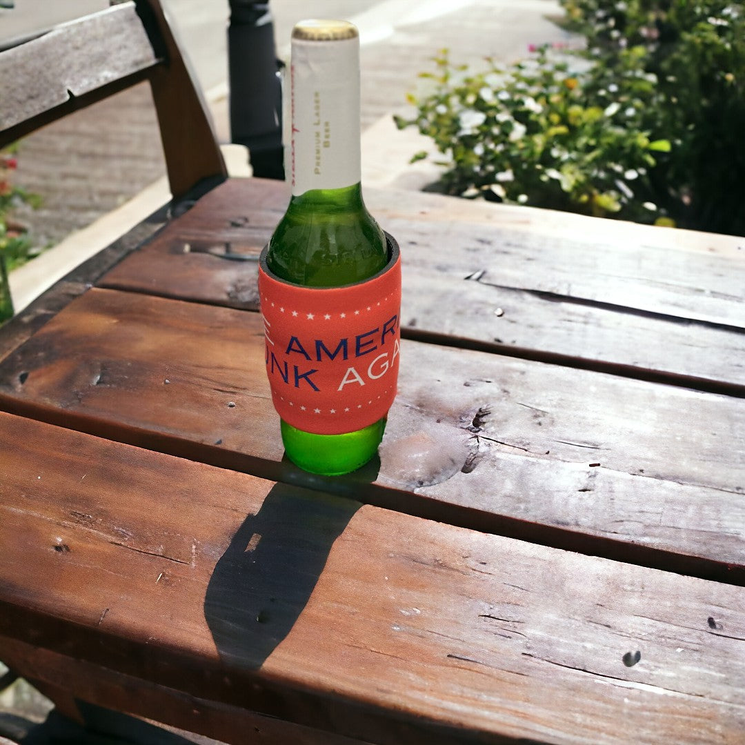 Outdoor shot of a beer bottle covered with a vibrant red koozie featuring 'Make America Drunk Again' text, perfect for personalized gift options