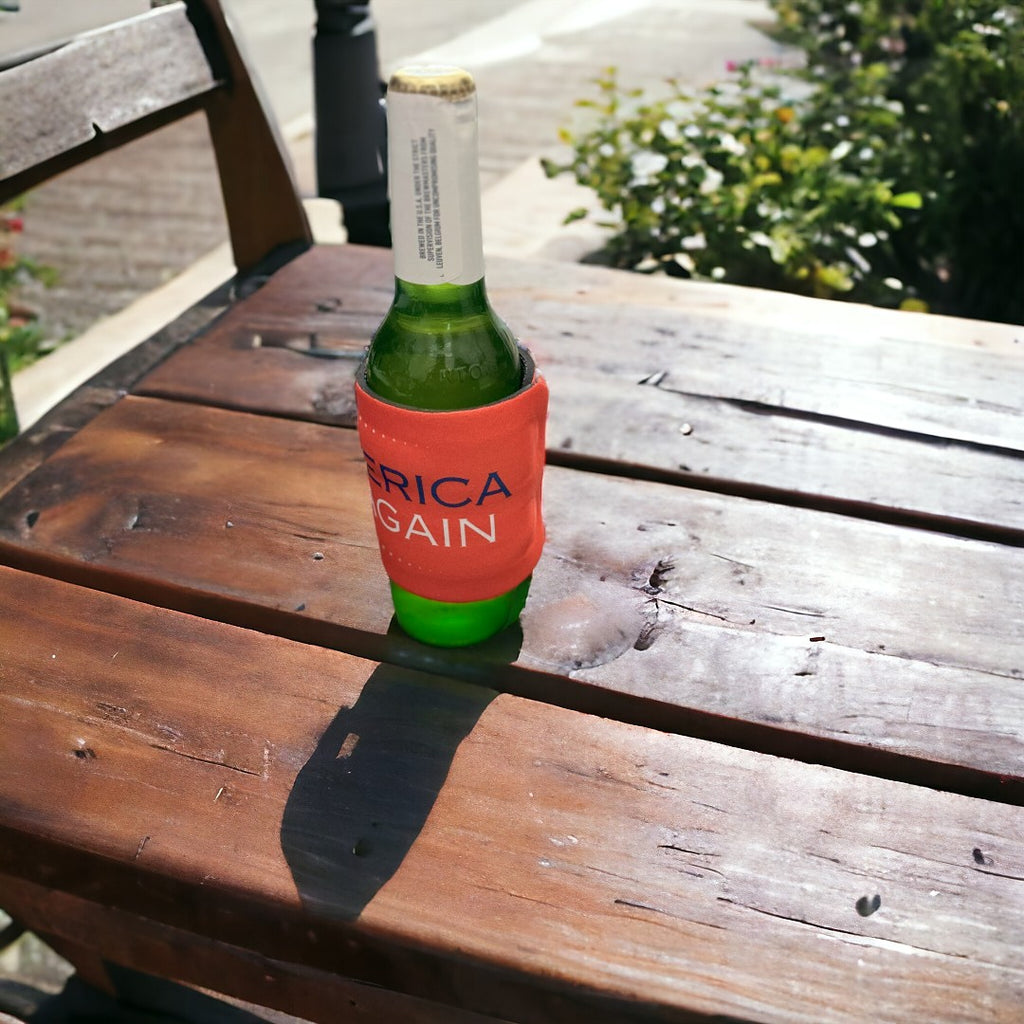 Outdoor shot of a beer bottle covered with a vibrant red koozie featuring 'Make America Drunk Again' text, perfect for personalized gift options