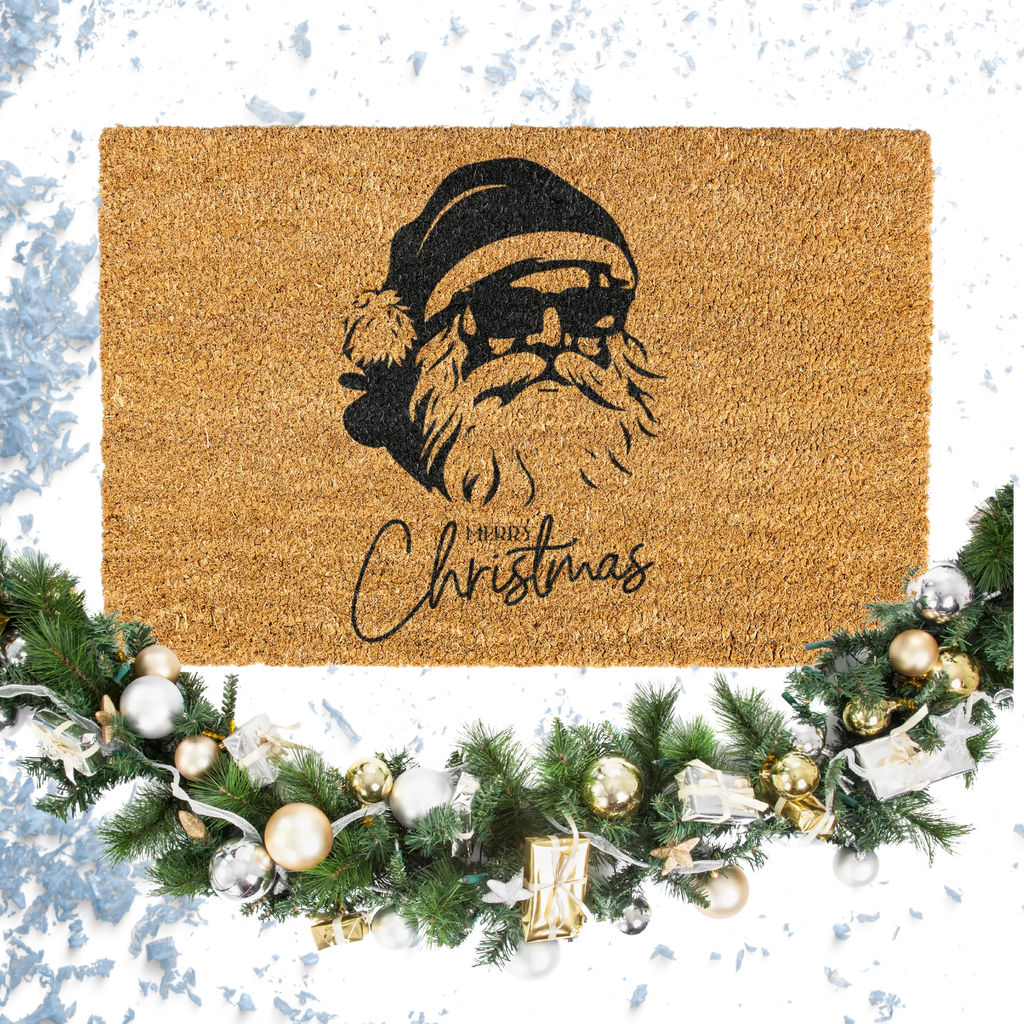 Doormat with Santa Claus design and 'Merry Christmas' text, surrounded by festive decorations on a snowy background.