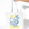 Tote bag with lemon design and text held by a hand on a white background