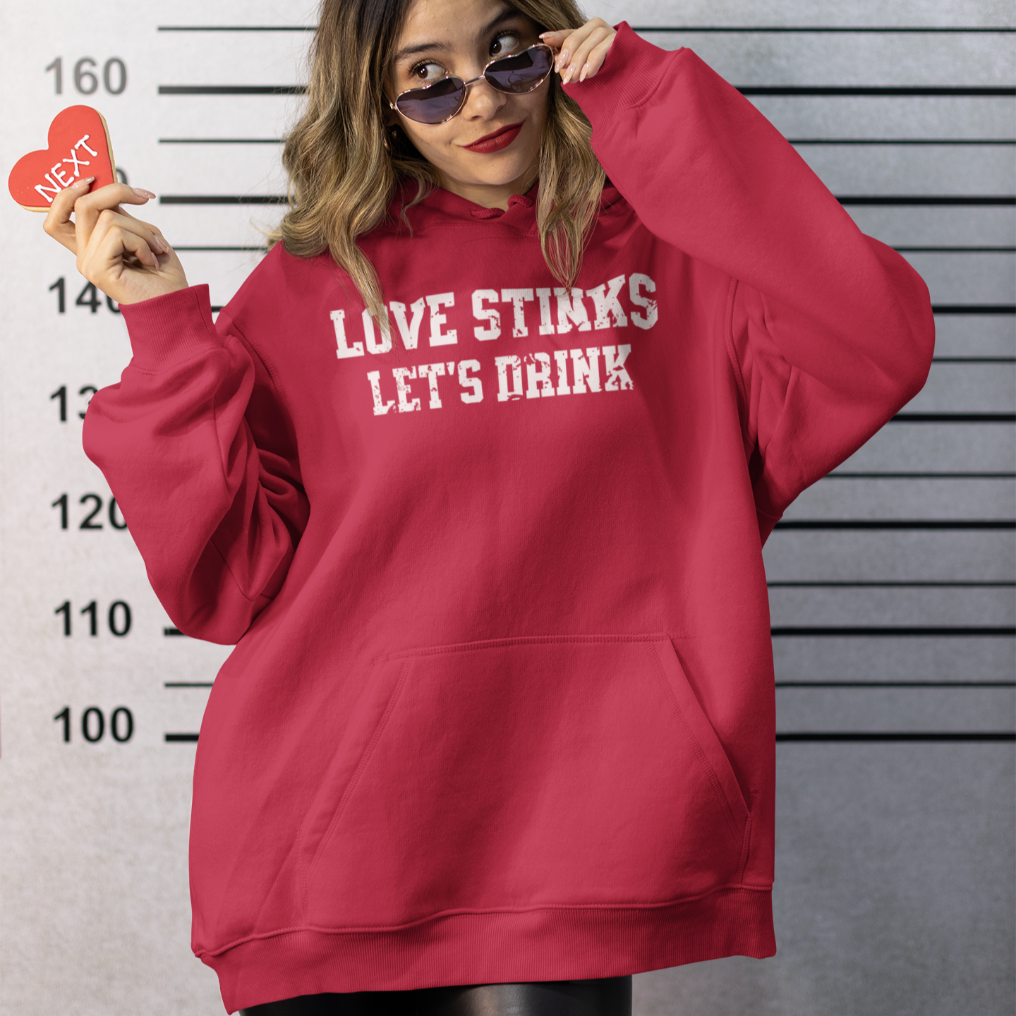 Red woman Valentine's hoodie with the phrase 'Love Stinks, Let’s Drink,' perfect for cozy anti-Valentine's Day vibes.