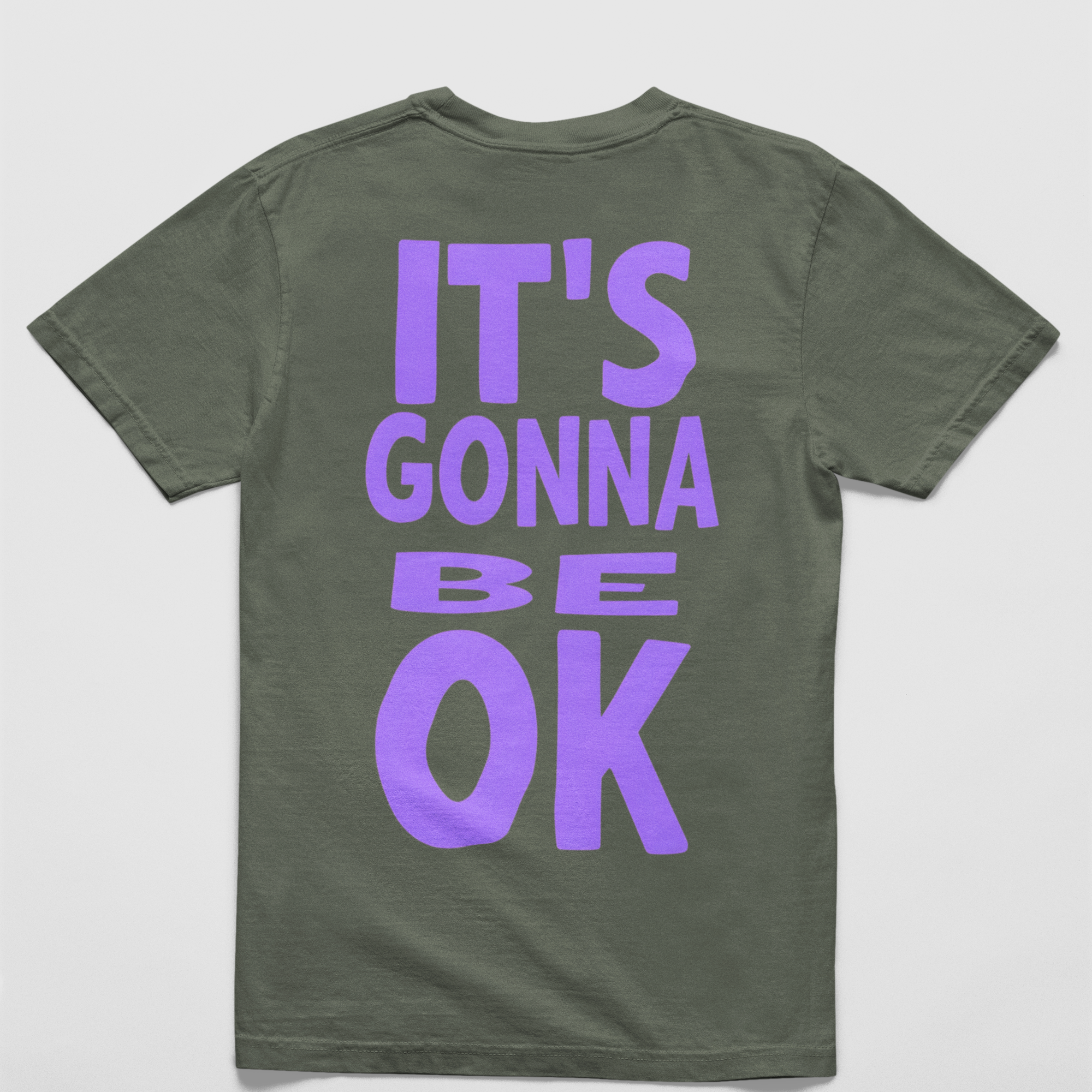 Oversized sage tee with "It’s Gonna Be OK" printed in bold purple text on the back, styled for casual and confident comfort.