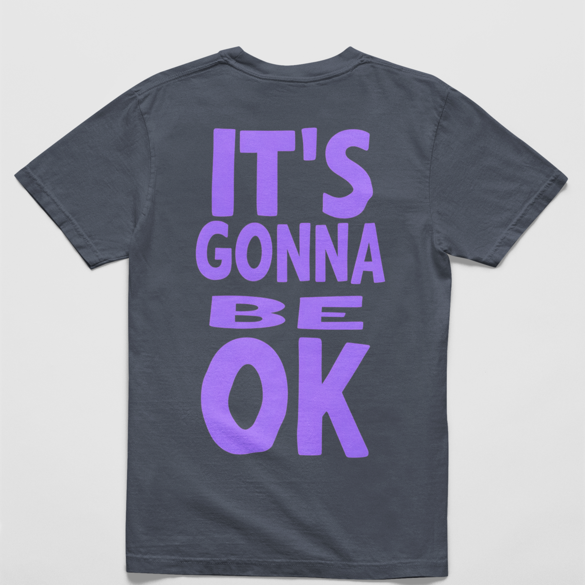 Oversized navy tee with "It’s Gonna Be OK" printed in bold purple text on the back, styled for casual and confident comfort.