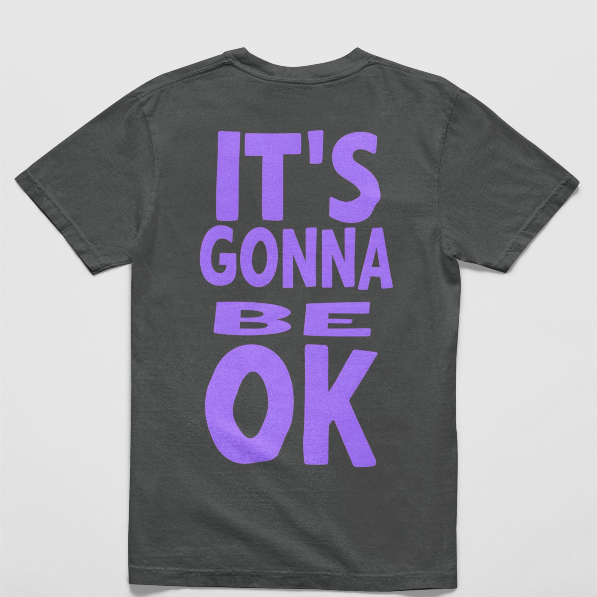 Charcoal Oversized black tee with "It’s Gonna Be OK" printed in bold purple text on the back, styled for casual and confident comfort.
