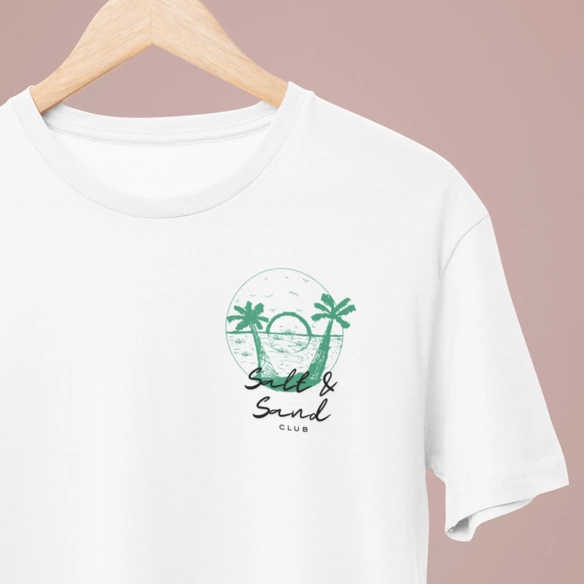 Minimalist left chest “Salt & Sand Club” graphic on white tee with palm trees and ocean sunset