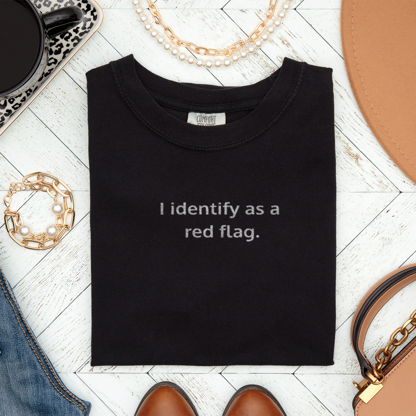 Folded black Comfort Colors t-shirt with “I identify as a red flag” design