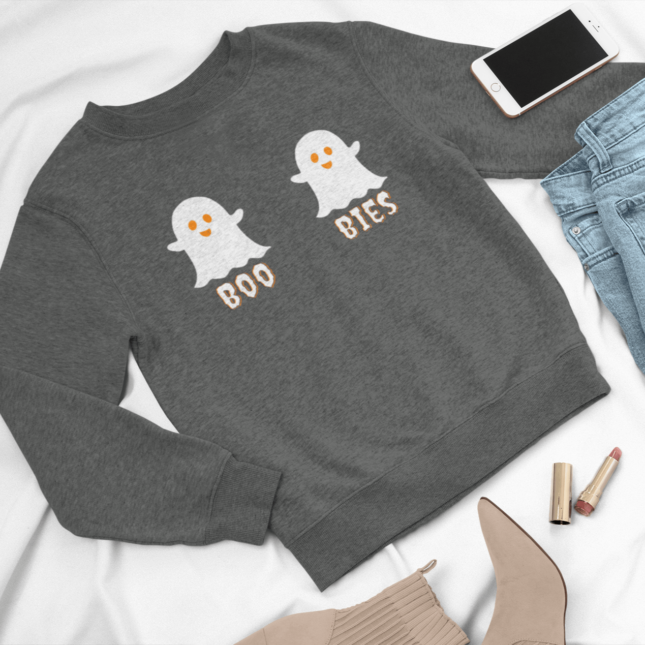 Gray cozy Halloween sweatshirt featuring two cute ghost illustrations with the playful text "BOO BIES," styled with jeans, a phone, and beige boots, perfect for casual festive wear.