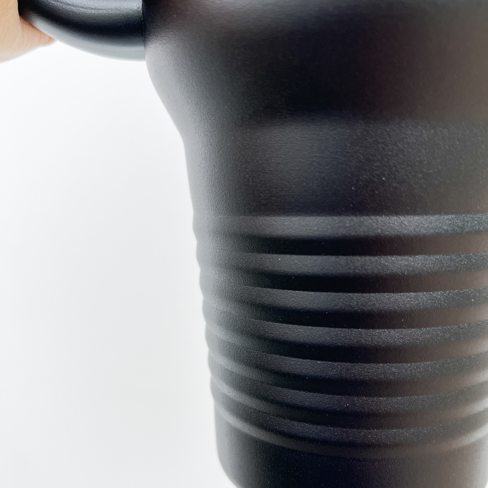 Close-up of a black tumbler with a clear lid, featuring a built-in straw and stainless steel rim