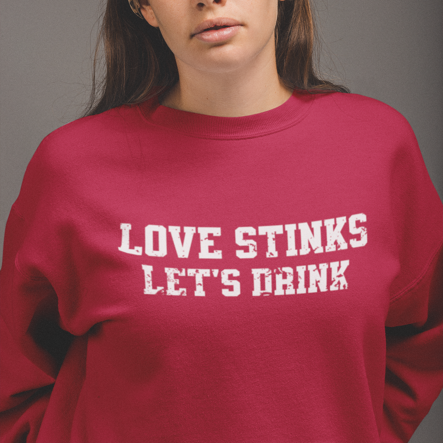 Red 'Love Stinks, Let's Drink' crewneck sweatshirt with bold white distressed lettering, perfect for cozy anti-Valentine's style.