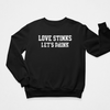 Black Flat Lay 'Love Stinks, Let's Drink' crewneck sweatshirt with bold white distressed lettering, perfect for cozy anti-Valentine's style.