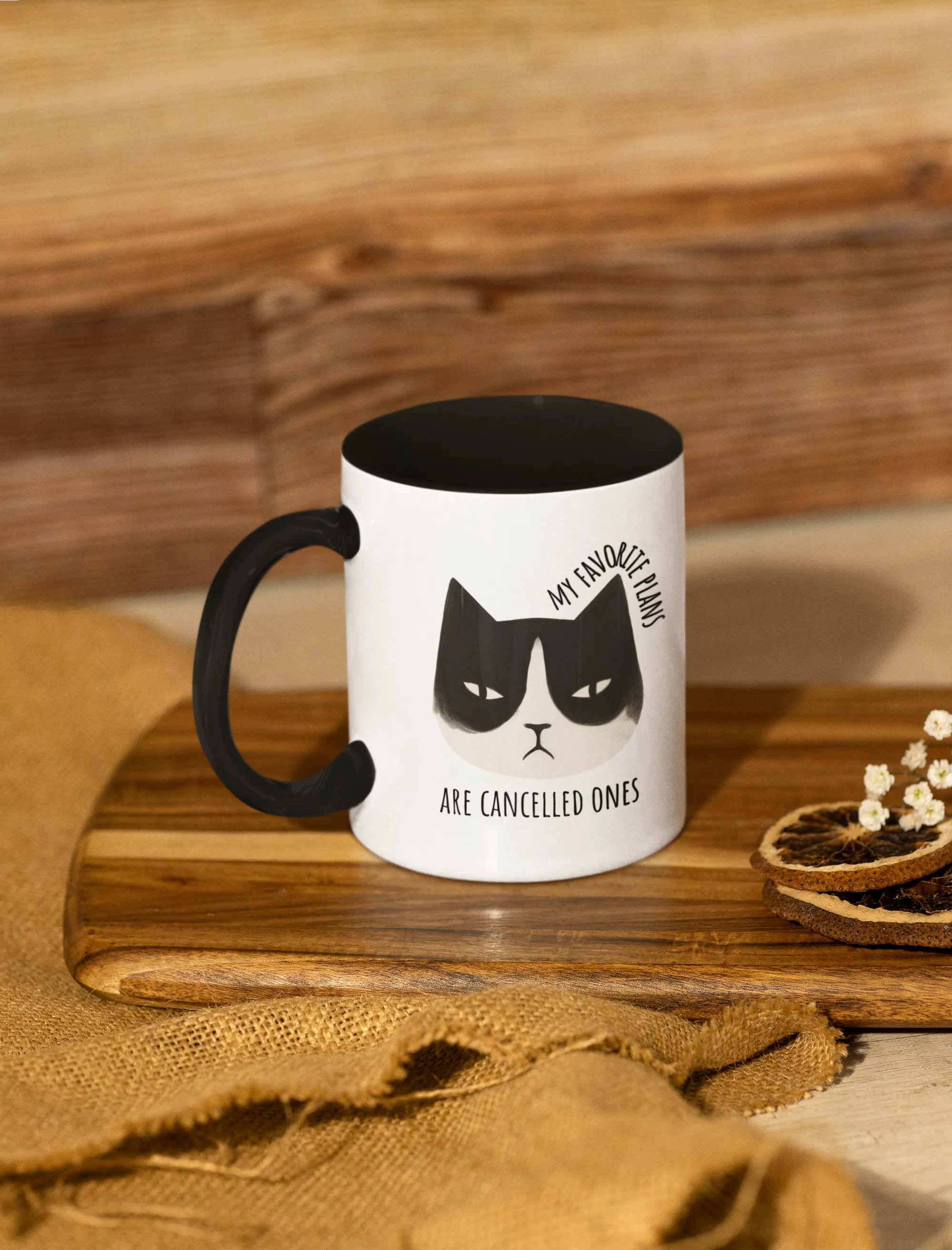 White mug with black cat illustration and text on a wooden surface