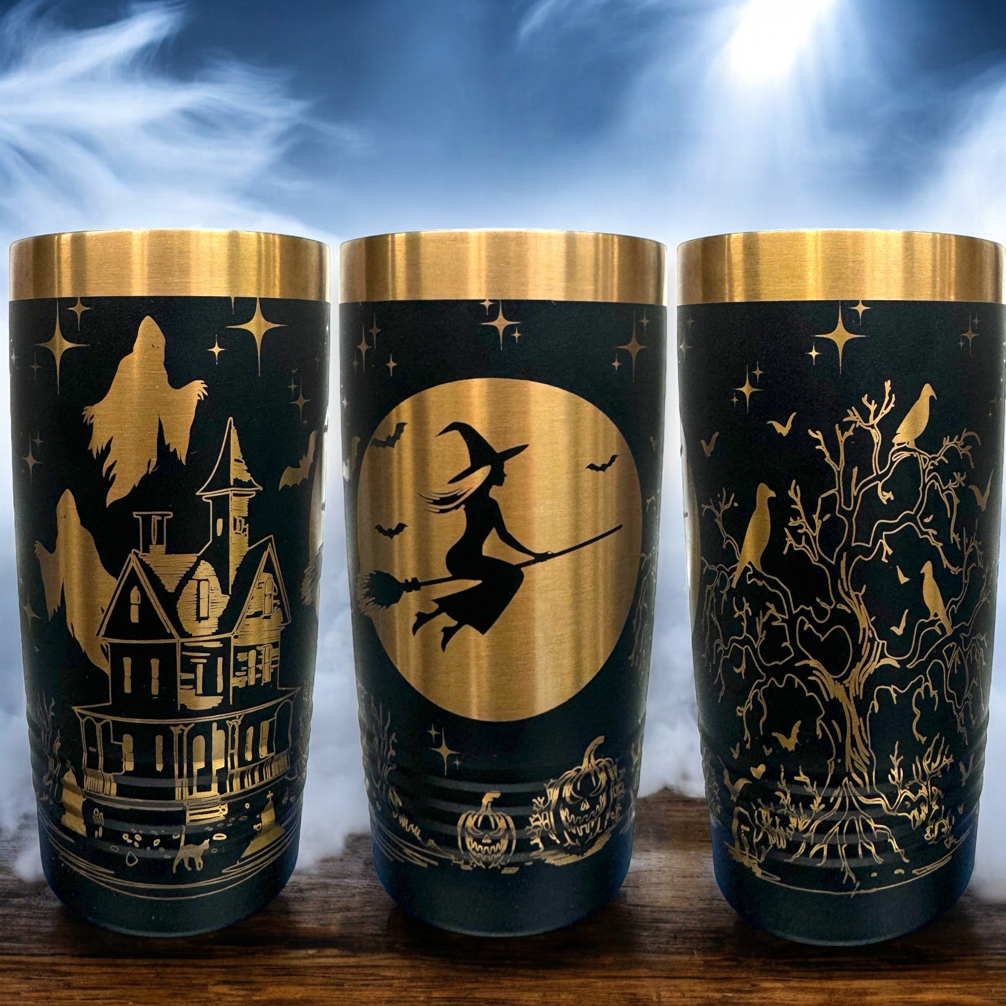 Three 20 oz laser-etched tumblers with gold accents, featuring Halloween-themed designs including a haunted house with ghosts, a witch flying on a broomstick, and a spooky tree with bats and crows. Perfect for festive or seasonal drinkware.