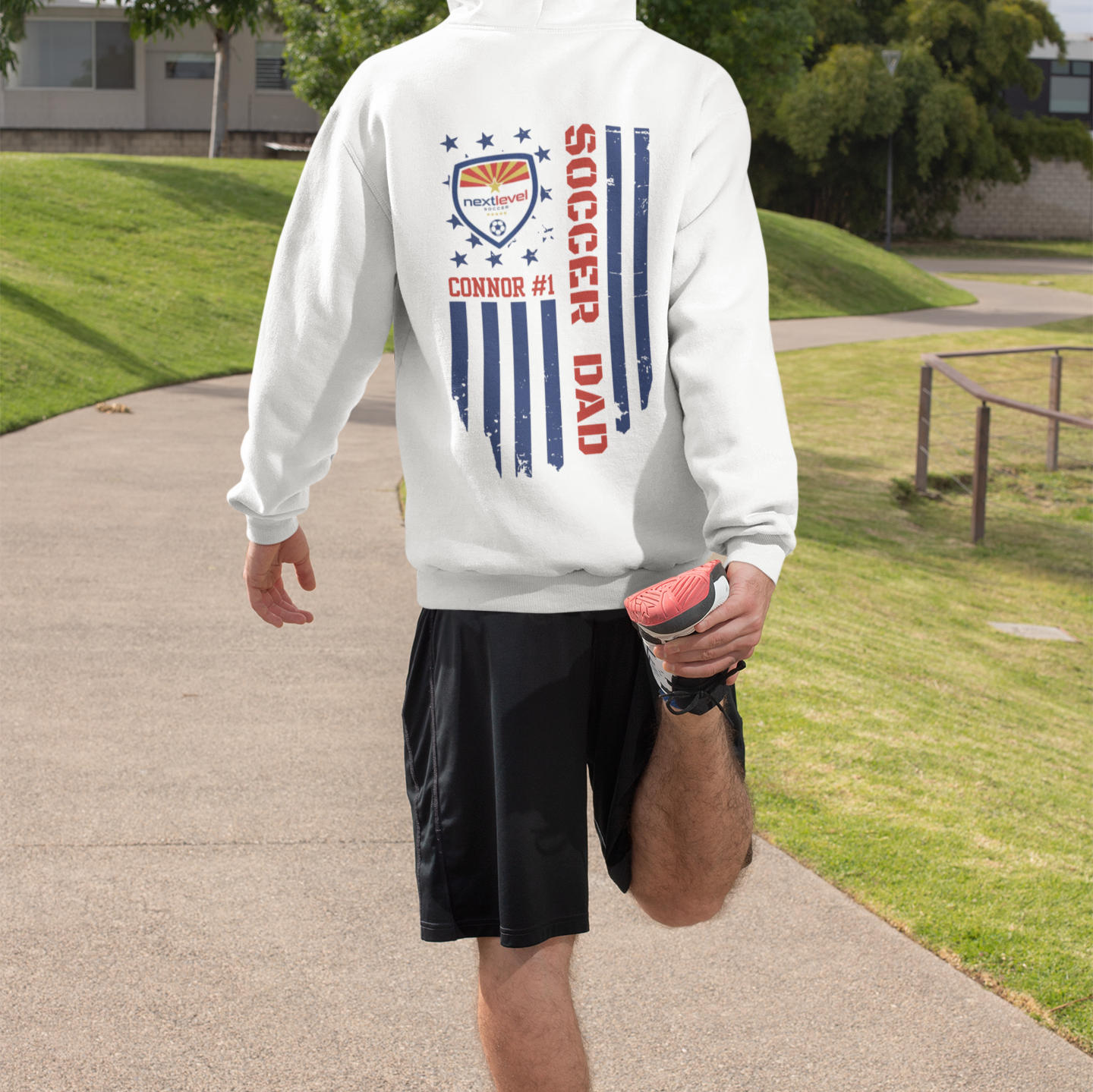 Man standing with customizable soccer team hoodies featuring team logo, player name, and number with color-matched flag and text, perfect for soccer fans and players