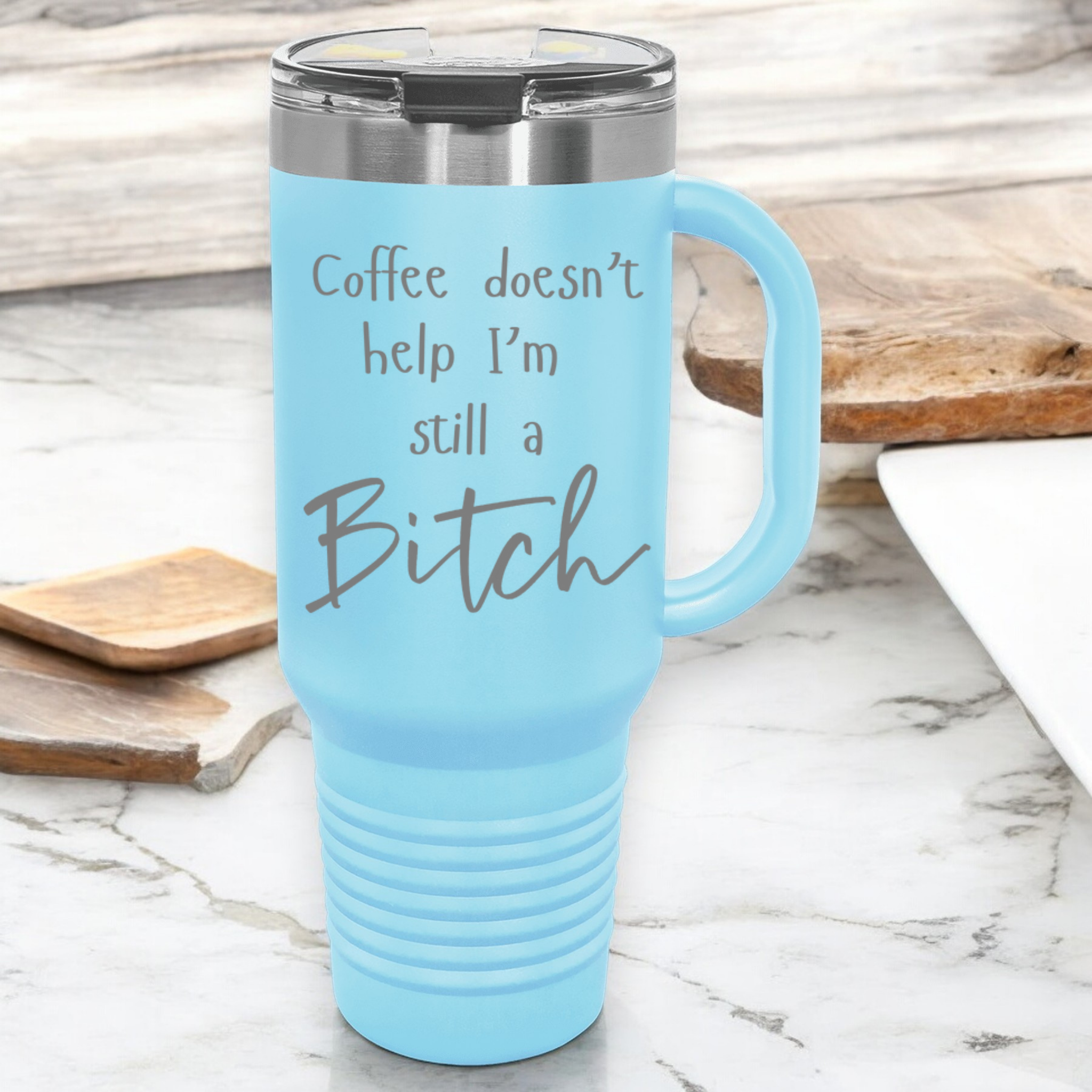 light blue 40 oz stainless steel tumbler with a lid, featuring the humorous engraved quote, "Coffee doesn’t help, I’m still a bitch," and a built-in handle.