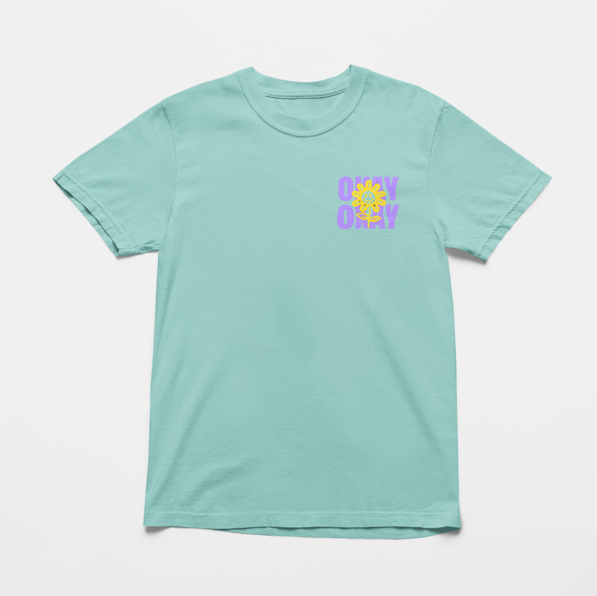 Oversized chalky mint tee with "It’s Gonna Be OK" printed in bold purple text on the back, styled for casual and confident comfort.