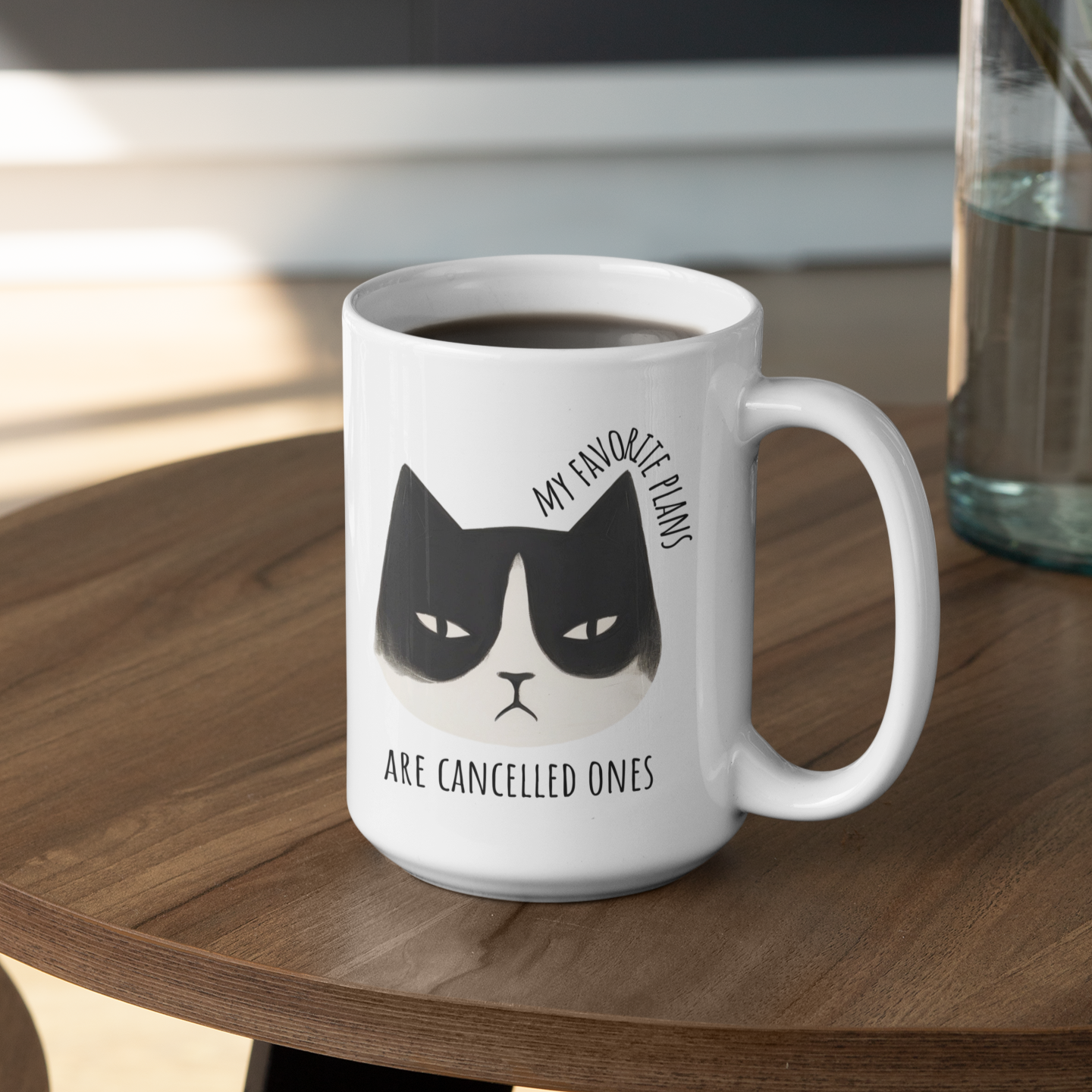 15 oz ceramic mug with cartoon grumpy cat and “My favorite plans are cancelled ones” text on table