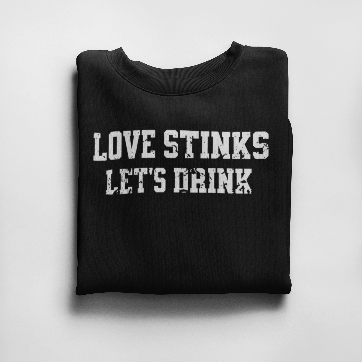 Folded Black 'Love Stinks, Let's Drink' crewneck sweatshirt with bold white distressed lettering, perfect for cozy anti-Valentine's style.