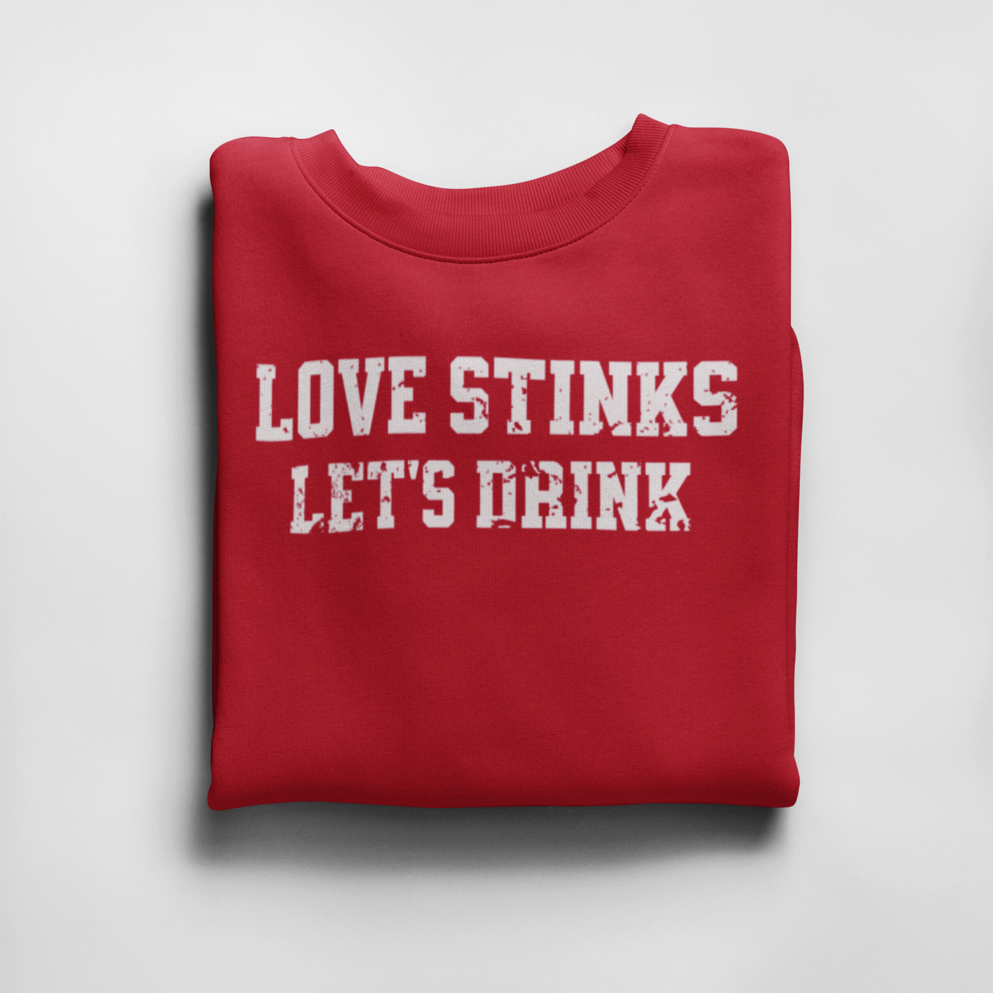 Red folded 'Love Stinks, Let's Drink' crewneck sweatshirt with bold white distressed lettering, perfect for cozy anti-Valentine's style.