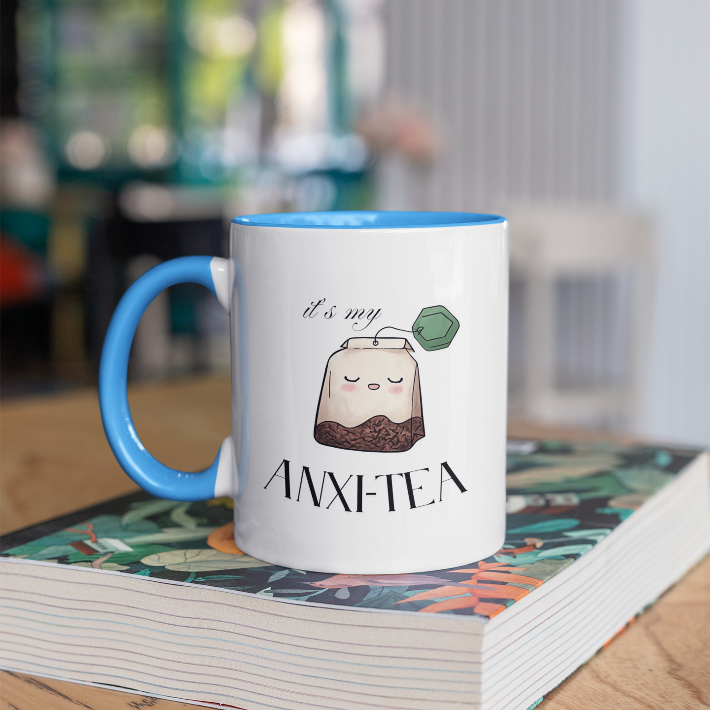 Funny 15 oz coffee mug with cartoon tea bag and “It’s My Anxie-Tea” mental health quote, with blue handles