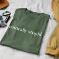 Woman sitting cross-legged outside wearing “naturally stupid” t-shirt in a lifestyle mockup
