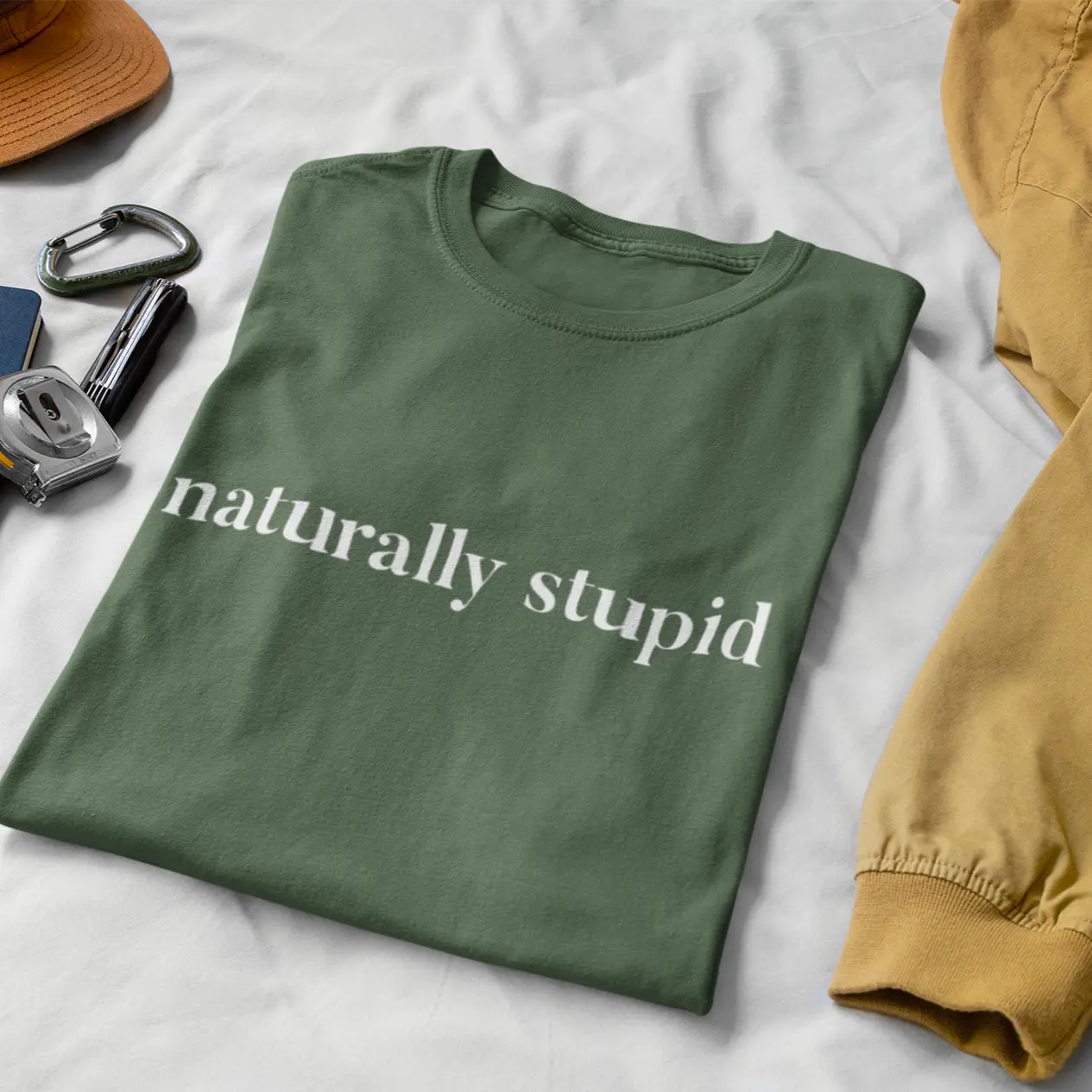 Woman sitting cross-legged outside wearing “naturally stupid” t-shirt in a lifestyle mockup