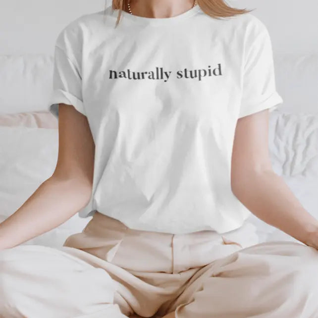 Outdoor lifestyle photo of woman sitting on a rock wearing “naturally stupid” t-shirt