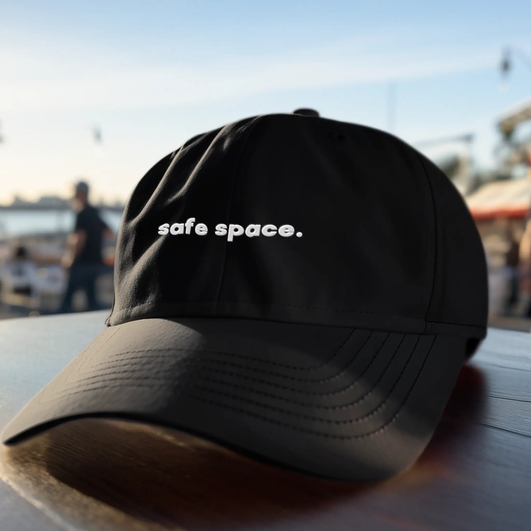 Close-up of white dad hat with “safe space.” embroidered text, LGBTQ ally pride accessory