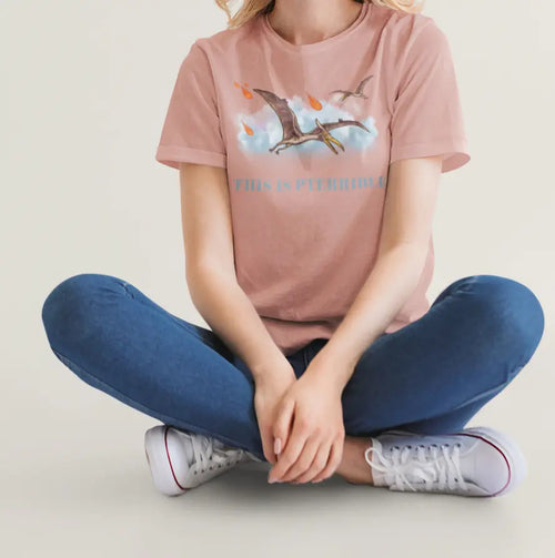 Woman sitting in a studio wearing “This Is Pterrible” graphic t-shirt with pterodactyl and meteors