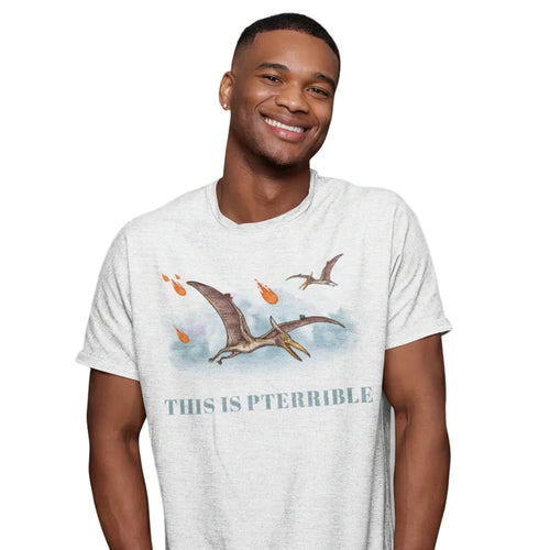 Man smiling in a studio wearing “This Is Pterrible” graphic tee with pterodactyl and meteor design