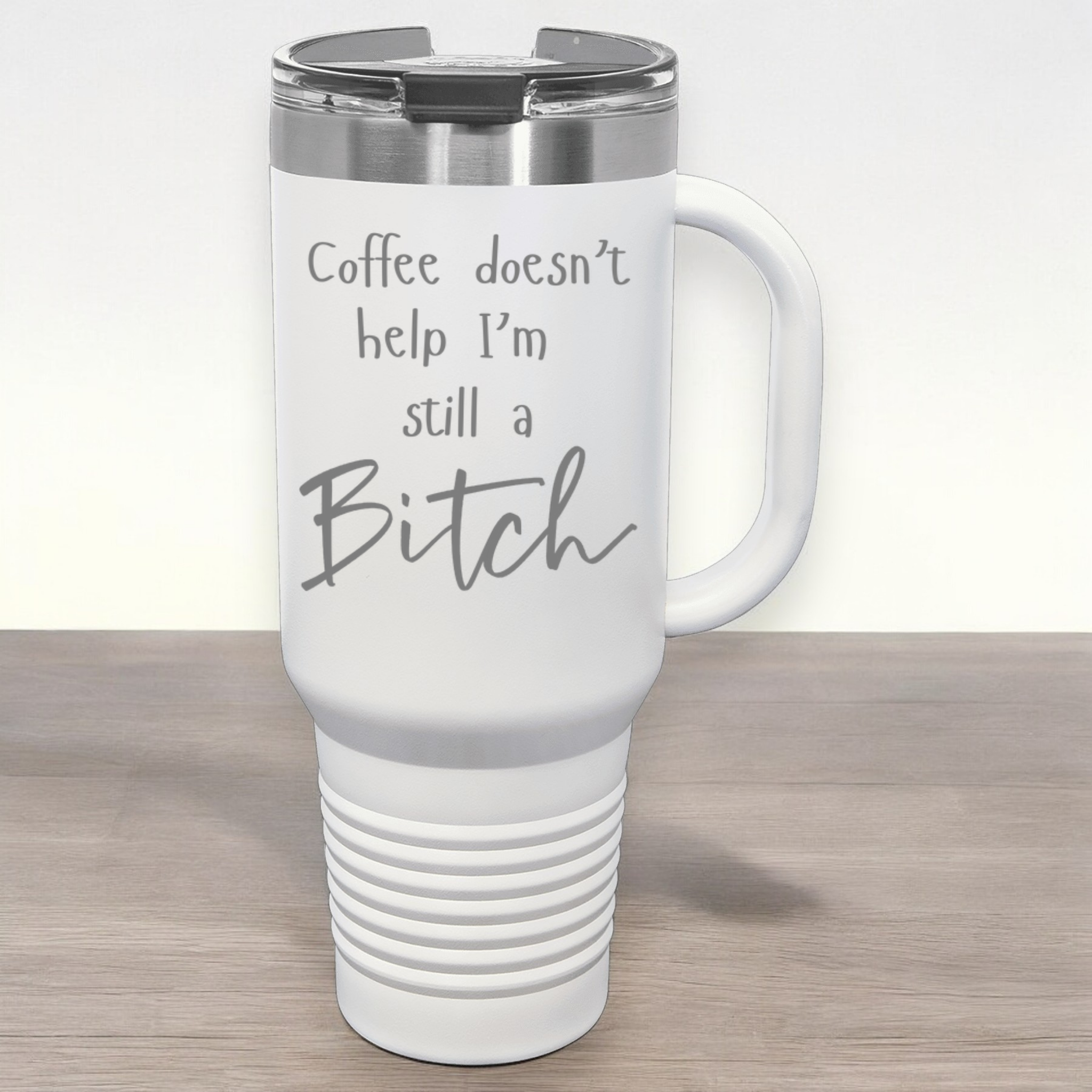 White 40 oz stainless steel tumbler with a lid, featuring the humorous engraved quote, "Coffee doesn’t help, I’m still a bitch," and a built-in handle etched
