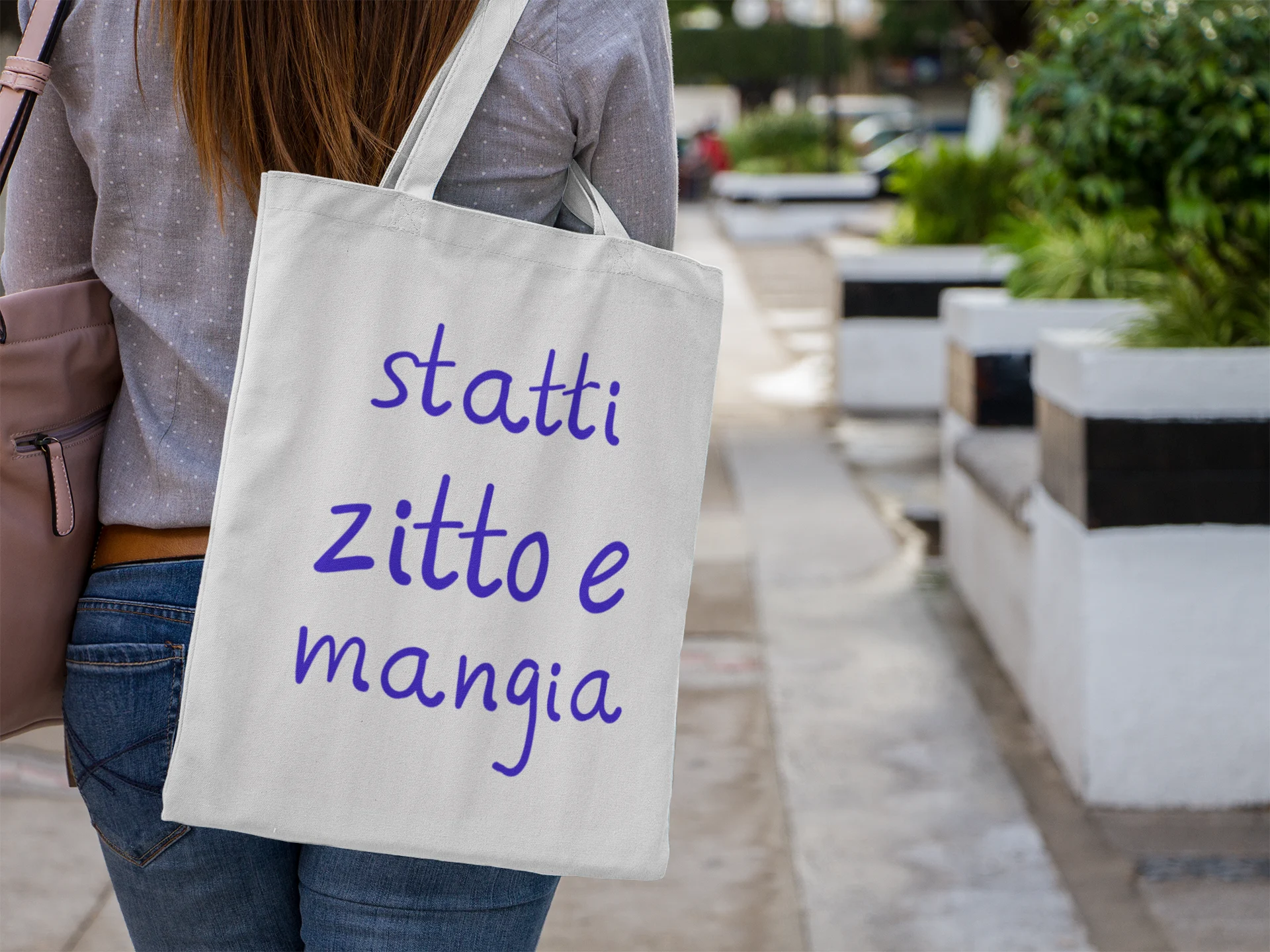 Person holding a tote bag with Italian text in an outdoor setting